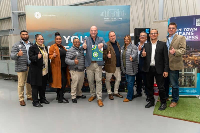 Cape Town news team at an event, group photo with thumbs up, diverse professionals in business attir.