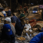 Refugees and families gather at night in Cape Town, South Africa, amid ongoing challenges, highlight.