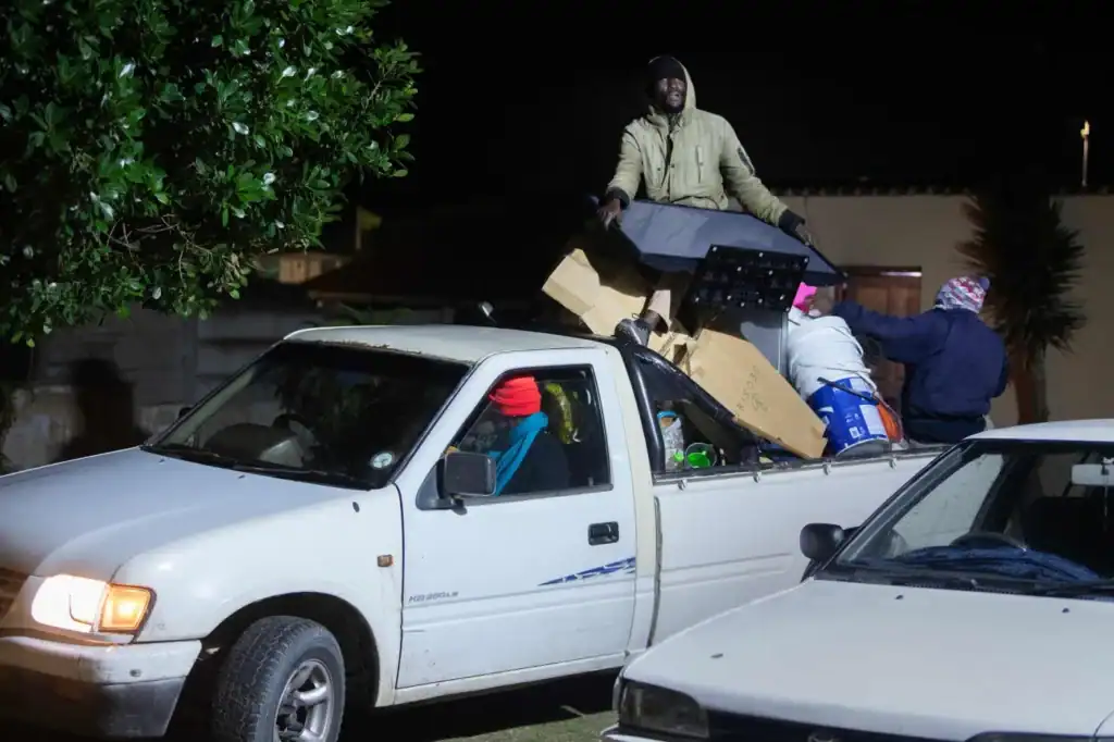 Night scene of people loading items into a white pickup truck in Cape Town.