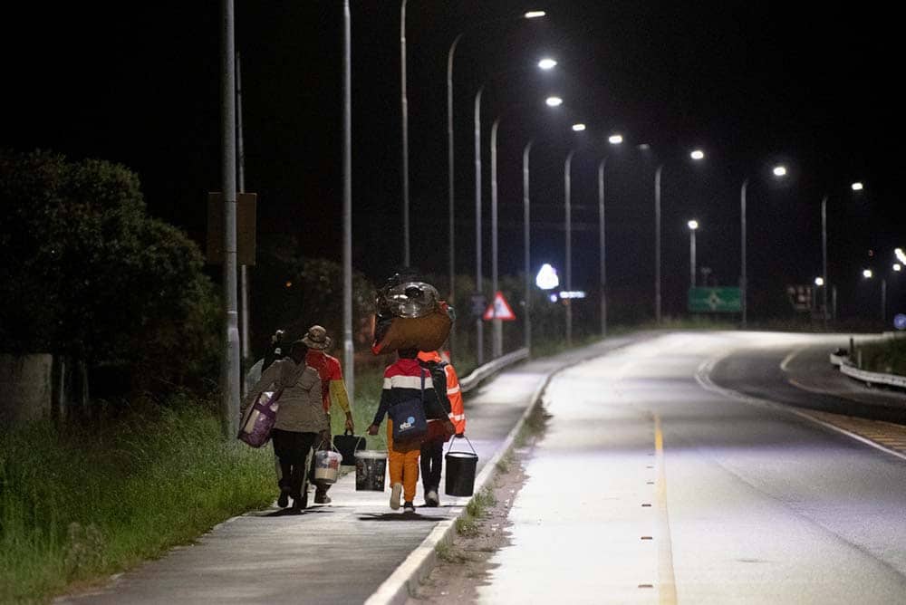 Lost travelers walking along a deserted road at night in Cape Town, South Africa.