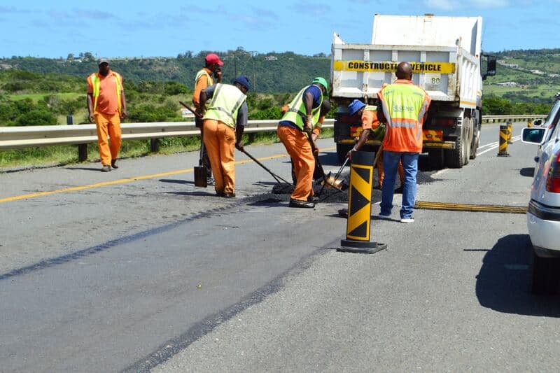 Road repair crew working on asphalt on Cape Town highway.