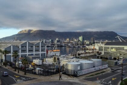 Cape Town harbor with Table Mountain in the background, under cloudy skies.