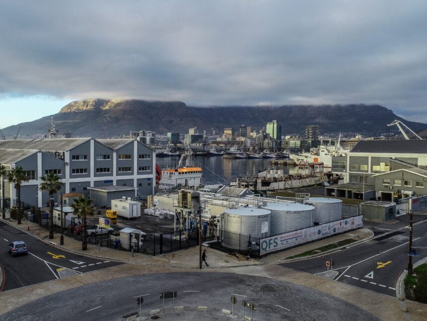 Cape Town harbor with Table Mountain in the background, under cloudy skies.