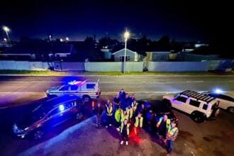 Emergency responders and police officers gather at night on a street in Cape Town, with police vehic.